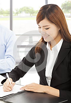 Young business woman writing document with colleague