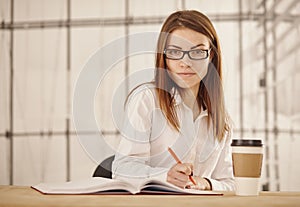 Young business woman writing in office.