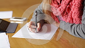 Young business woman writing pen on sheet of paper at office