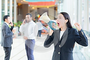 Young business woman working at the office, shouting and yelling in megaphone