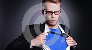 Young businessman acting like a super hero and tearing his shirt, on gray background