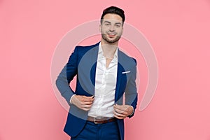 Young businessman adjusting his jacket and smiling