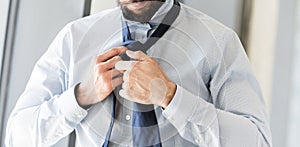 Young businessman adjusting his neck tie in office