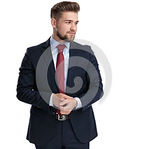 Young businessman adjusting his sleeve and looking to the side