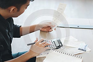 Young businessman in black shirt calculating his bill by using a calculator, thinking about his financial information and debt