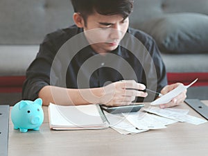 Young businessman in black shirt calculating his bill by using a calculator, thinking about his financial information and debt