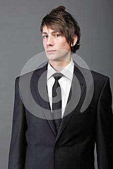 Young businessman black suit casual tie on gray background