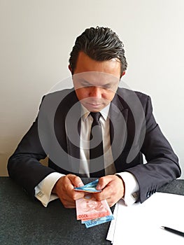 young businessman with black suit counting Costa Rican money