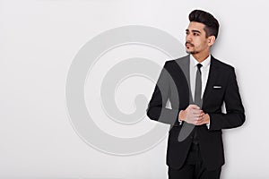 Young businessman in black suit on a white background. Confident man looking away from the camera.