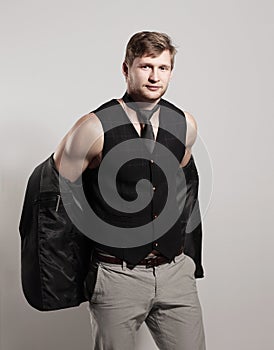 Young businessman in a business suit without a shirt holds a jacket over his shoulder