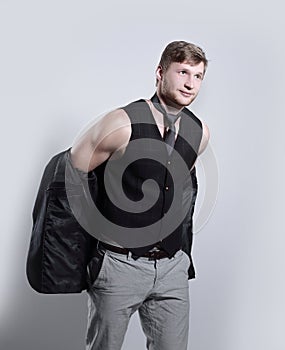 Young businessman in a business suit without a shirt holds a jacket over his shoulder