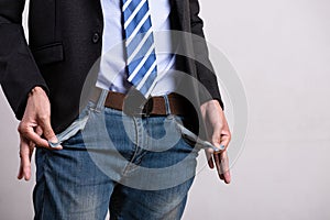 A young businessman in a business suit showing his empty pockets. Financial difficulties, bad economy, no money concept