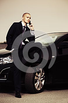Young businessman calling on cell phone by car