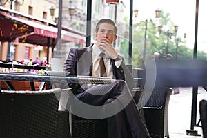 A young businessman came to lunch in a cafe, he sits at a table and talking by smartphone with bad emotions