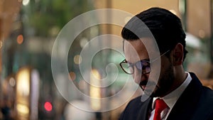 Young businessman checking lateness time on wrist watch at night