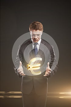 Young businessman chooses a Gold Euro Sign.