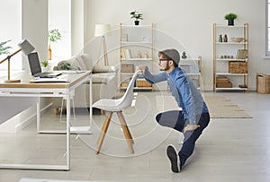 Young businessman combines work and healthy lifestyle doing sports in his home office.