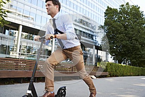 Young Businessman Commuting To Work Through City On Scooter