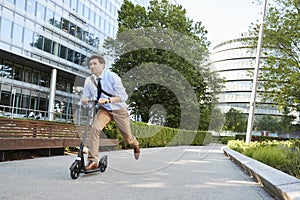 Young Businessman Commuting To Work Through City On Scooter