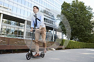 Young Businessman Commuting To Work Through City On Scooter