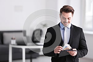 Young businessman counting money indoors. Money savings concept