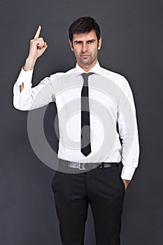 Young businessman criticizing on gray background