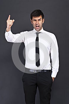 Young businessman criticizing on gray background