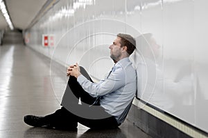 Young businessman crying abandoned lost in depression sitting on ground subway
