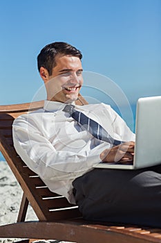 Young businessman on a deck chair using his computer