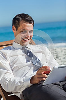 Young businessman on a deck chair using his tablet