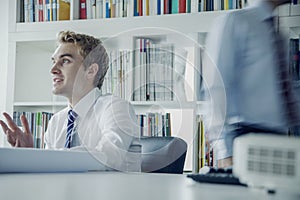 Young businessman discussing at a business meeting with colleague behind him