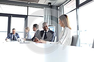 Young businessman discussing with female colleague in board room