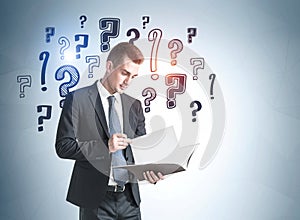 Young businessman with document and question marks