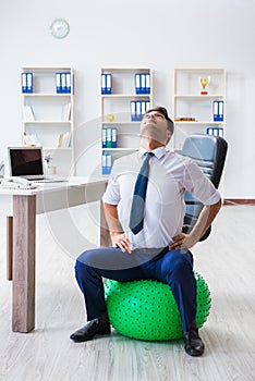 The young businessman doing sports stretching at workplace