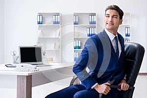 The young businessman doing sports stretching at workplace