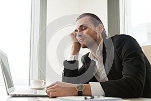 Young businessman dozed in front of laptop at work.