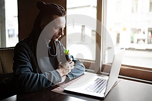 Young Businessman with dreadlock having doing his work in cafe with laptop