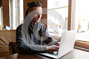 Young Businessman with dreadlock having doing his work in cafe with laptop