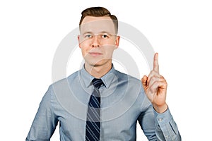 Young businessman dressed in blue shirt and tie shows index finger up, isolated on white background