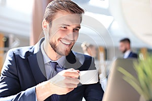 Young businessman drinking coffee in office while typing on computer