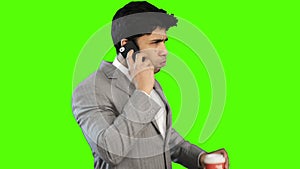 Young businessman drinking coffee while talking on cell phone