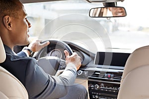 Young businessman driver sitting inside car looking aside cheerful back seat view