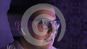 Young businessman in earbuds talking in front of the computer, pan shot