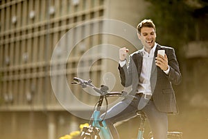 Young businessman on the ebike received gret news by mobile phone