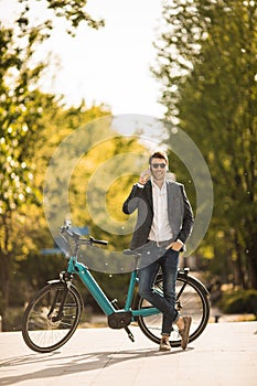 Young businessman on the ebike using mobile phone