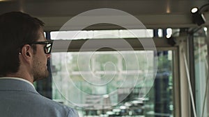 A young businessman, an employee of a large company walks around a modern beautiful office and greets, waves his hand