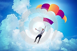 The young businessman falling on parachute in business concept