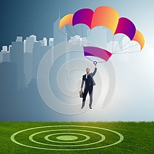 Young businessman falling on parachute in business concept