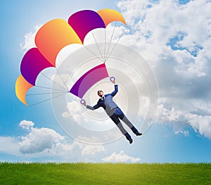 Young businessman falling on parachute in business concept