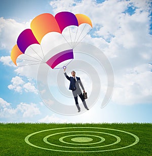 Young businessman falling on parachute in business concept